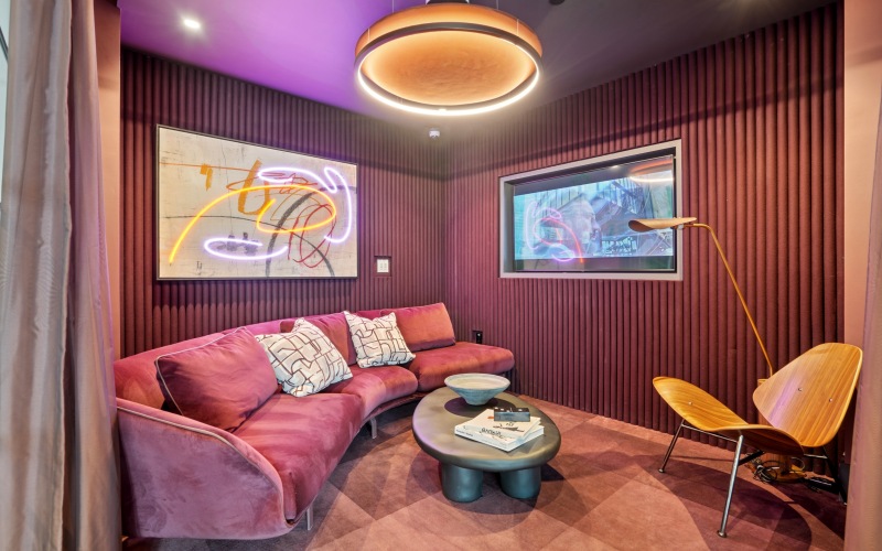 a room with a maroon couch and a tv on the sound proofed walls